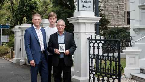 Four generations of Goldsmiths standing outside Alfred Nathan House. Paul, Oliver, and Lawrence holding a photo of his father, Rex.