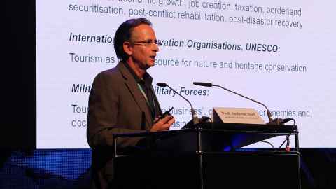 Professor Andreas Neef speaking at a podium