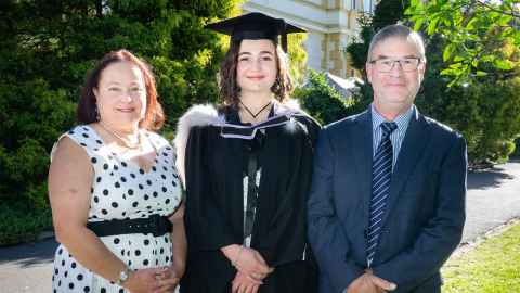 Judith Glasson, wearing academic regalia, standing in the grounds outside Old Government House