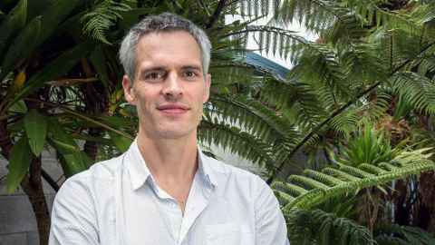 Associate Professor Jay Marlowe standing amongst ferns and trees outside a building