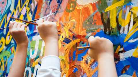 Three children's hands holding paintbrushes