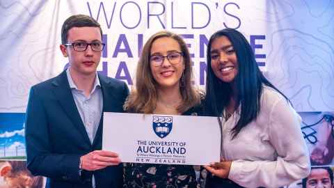 Henry Frear, Arianna Bacic, and Ishie Sharma holding a sign with the University of Auckland logo