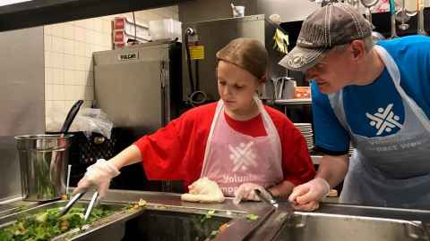  James Hosking and daughter Lucy wearing Volunteer Impact Week T-shirts, working in a kitchen.