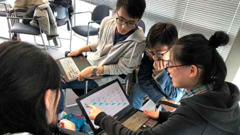 Four students from Southwest University in China seated and looking at laptops