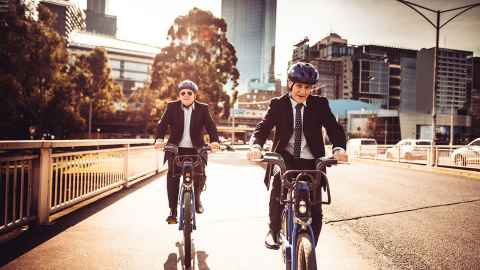 Two men in suits riding bikes