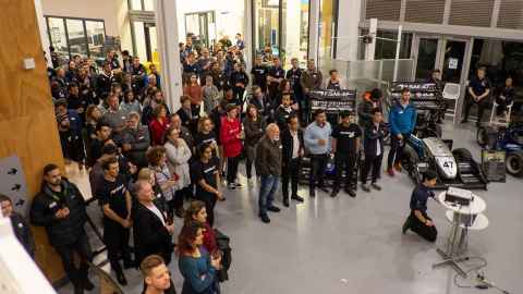A crowd of people in a room with racecars