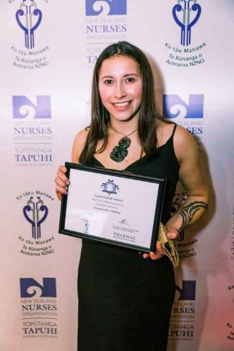 Tumanako Bidois holding an award certificate.