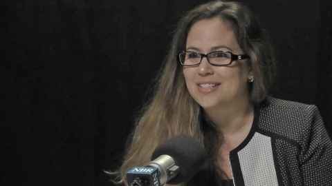 Nikki Chamberlain speaking into a microphone with an NBR logo.