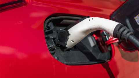 A charger plugged into a red EV