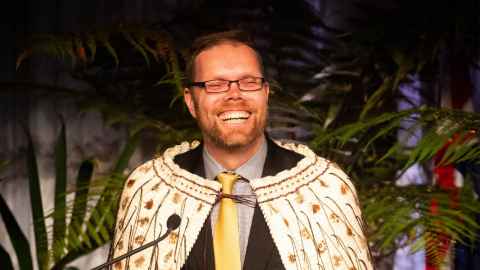 Andrew Eberhard, wearing a korowai, speaking into a microphone