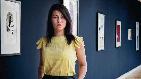 Imogen Kerr standing next to framed prints and paintings on a wall.