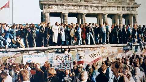The photo is an iconic image of West and East Germans meeting at the Brandenburg Gate as the Berlin Wall fell in November 1989. Photo: Wikipedia Commons.