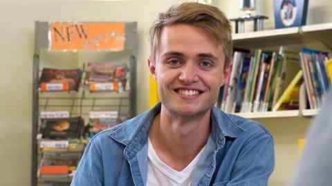 Blake Pattison in front of shelves of children's books