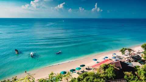 Boats and sun umbrellas on a tropical beach.