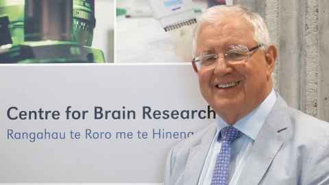 Sir Richard Faull next to a sign saying "Centre for Brain Research, Rangahau te Roro me te Hinengaro"