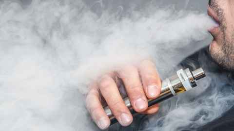 Person using a vape and exhaling 