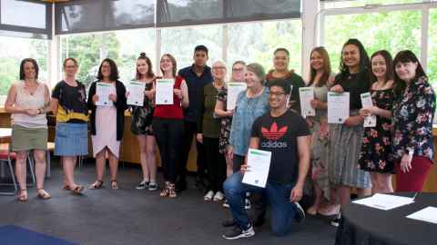 A group of fifteen students holding certificates