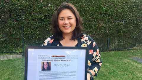 Dr Maria Cooper holding a framed award certificate
