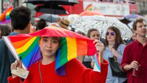 A woman holding a rainbow flag above her head