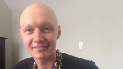 Alex Hunt with a shaved head and wearing beads around his neck.