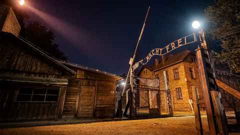An image showns a night time view of Auschwitz I: Main Gate. From the exhibition "Auschwitz. Now.” Image: © Copyright 2019 Perry Trotter