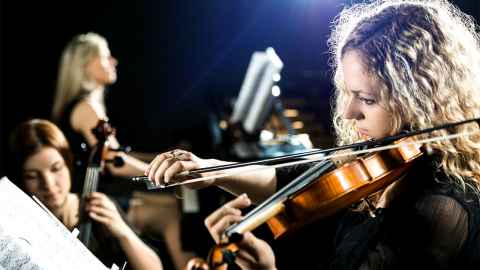 A young female violinist is pictured at the forefront of an orchestra: The decision to downgrade RNZ Concert raises the question of how important it is to support the arts in NZ. Photo: iStock