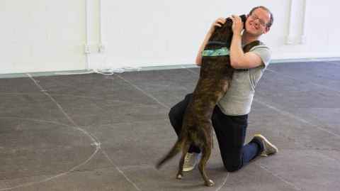 Patrick Neilands hugging a dog which is licking his face