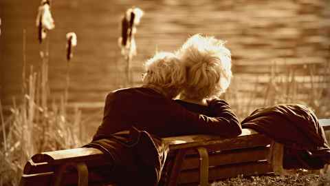 A comfortable-looking older couple relax by a lake: A lot of young people's money is going towards pensioners who don't need it. Stock photo: Pixabay