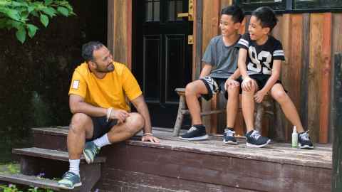 A father is shown talking with his two sons: Children take their cues from adults. So if you display anxiety, they will pick up on it. Photo: iStock