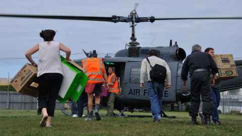 Volunteers are pictured rushing to a helicopter to unload supplies: Voluntary organisation and their armies of volunteers were essential to the rescue operation following the Christchurch earthquakes. Photo: iStock