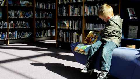 Child reading a book in a library