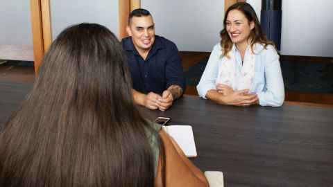 A trio of young New Zealanders sit at a business meeting: Young New Zealanders at the start of their careers must have employment opportunities and not pay the price of Covid-19 alone. Photo: iStock