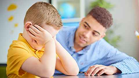 A male teacher is pictured talking to an unhappy young boy with his head in his hands: Caring for a child’s well-being and safety is an integral part of teaching but little training is provided in precisely what this involves. Photo: iStock