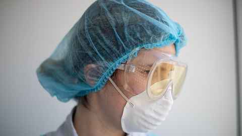Person wearing a white mask, goggles and a blude hair cap.