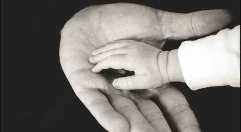 Adult and child hands resting on each other 