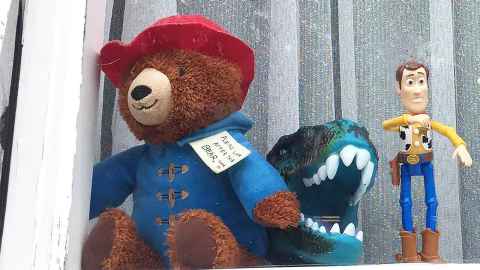 Paddington bear, a dinosaur and Woody from Toy Story on a windowsill.