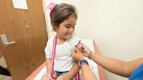 A little girl having a band aid put on her arm after a vaccination.