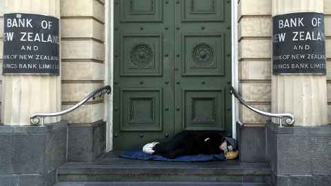 A homeless person asleep on the doorstep of a city building.