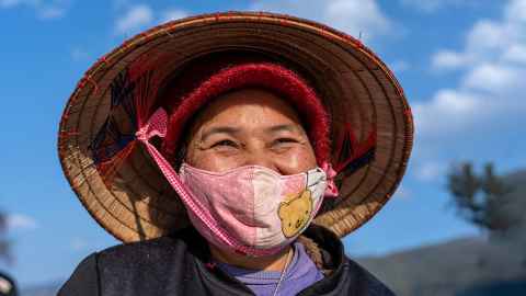 The image shows an older woman wearing a facemask in Sapa, North Vietnam. Photo: iStock
