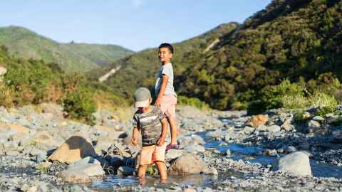 Two young boys are pictured playing in a rocky stream in a New Zealand landscape: Play could be the key to unlocking our children’s emotional well-being during these strange times. Photo: iStock