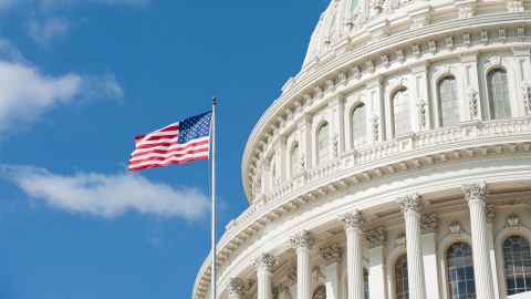 The immage shows a close up of the white dome of the Capitol Hill building with a US flag fluttering to the side: Joe Biden's inauguration took place in peace at Capitol Hill just two weeks after Trump-supporting rioters stormed the seat of US democracy. Photo: iStock