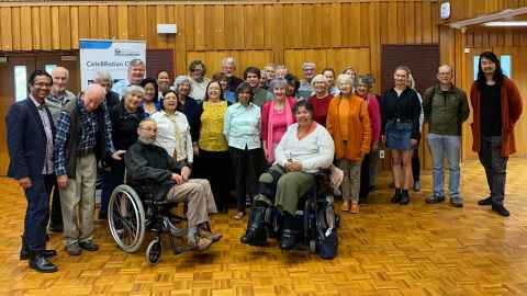 A large group of people; two are in wheelchairs.