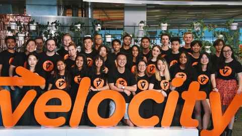 A large group of people in matching t-shirts with a sign that says 'Velocity'.