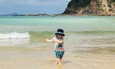 A child wading in shallow water at a beach.