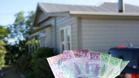 Bank notes held out in front of a house.
