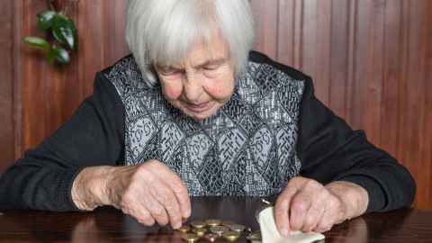 The image shows an elderly woman counting up coins from her purse: Lower earnings-related pension income and longer life expectancy are among the main drivers of higher poverty incidence among women than among men. Photo: iStock