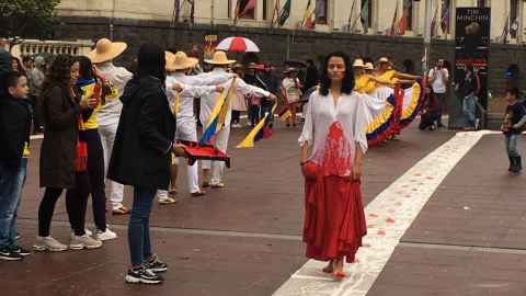 The image shows performance artist and article co-author Alejandra Jaramillo Aristizabal in the foreground wearing a white shirt coated in red paint to represent blood and fellow Colombians dancing in national dress in the background: Bringing the voice of Colombians to Aotea Square on Sunday and showing support for the people making anti-government protests in their home country. Photo: Supplied