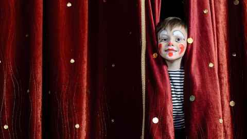 A child wearing face paint, looking through curtains.