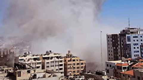 The image shows smoke rising from office buildings: The Israeli Air Force bombs an office building in Gaza, May 2021. Photo: Osps7, CC BY SA 4.0 via Wikimedia Commons