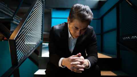 The image shows a man in a business suit sitting in a darkened stairwell of an office building looking upset: A culture of bullying in the workplace must be replaced by a culture of kindness. Photo: iStock